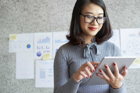 Woman looking down at a tablet in her hands.